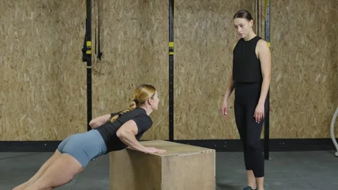 Athletes demonstrate slow motion push-ups and box jumps in a gym setting Stock Footage 321397459