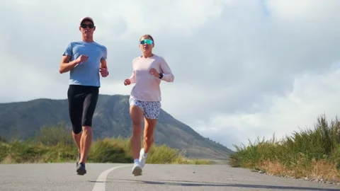 Athletes jog through cloud covered mountains, building endurance with a breeze. Stock Footage 301501270