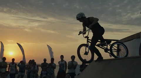 Athletes Making Jumps And Tricks on a Bike on sunset background. Bmx-vert Stock Footage 60714609