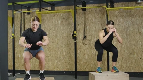 Athletes perform box jumps for strength training at a fitness center Video stock 327077774