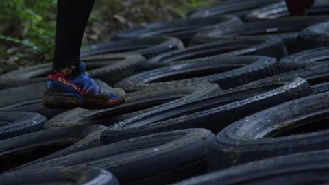 Athletes racing through obstacles and tires in fitness competition Stock Footage 70568923