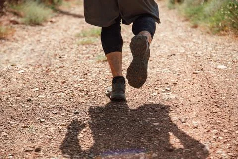 Athletes runner running down a mountain trail. A man runs through the mountai Stock Photos