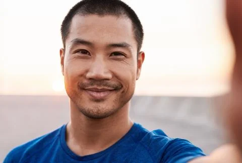 Athletic Asian man smiling while out for a morning run Stock Photos