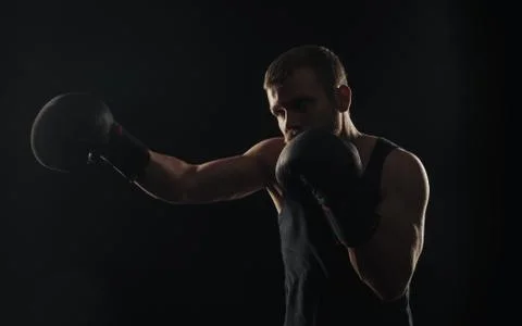 Athletic bearded boxer with gloves on a dark background Stock Photos
