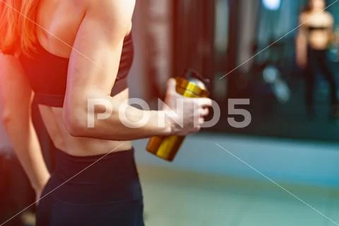 Athletic body of a woman with shaker in fitness center, looking at mirror. Pe Stock Photos