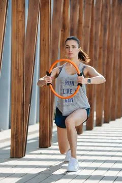 Athletic brunette doing pilates exercise with a hoop under wooden frame Stock Photos