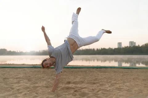Athletic capoeira performer workout training on the beach sunris Stock Photos