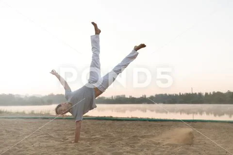 Athletic capoeira performer workout training on the beach sunris Stock ...