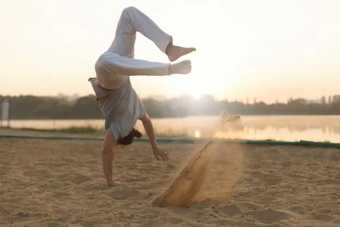 Athletic capoeira performer workout training on the beach sunris Stock Photos