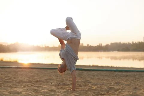 Athletic capoeira performer workout training on the beach sunris Stock Photos