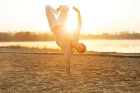 Athletic capoeira performer workout training on the beach sunris Stock Photos