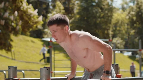Athletic caucasian shirtless man practicing dips on parallel bars training Video stock 242751472