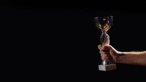 Athletic champion holding silver trophy cup against dark background. Stock Footage 334843277