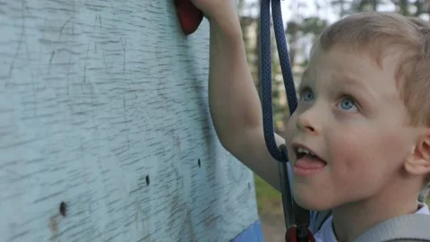 An athletic child boldly climbs up the climbing wall without fear of heights Stock Footage 223309064