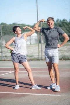 Athletic couple checking their muscles Strong biceps, doing sport exercises Stock Photos