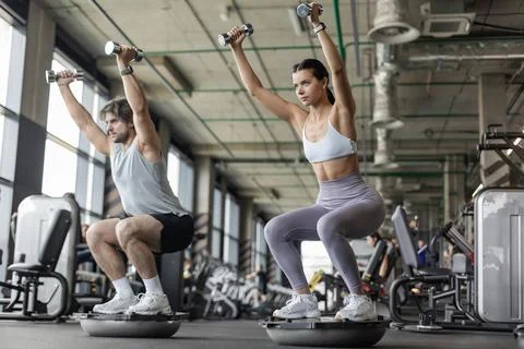 Athletic couple doing exercise on BOSU ball at gym Stock Photos