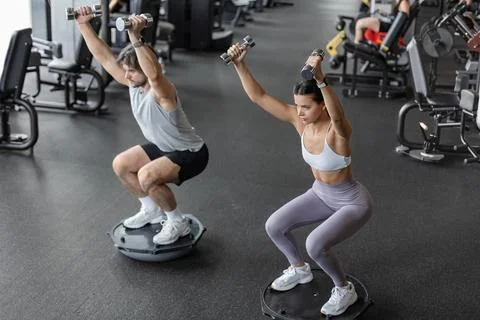 Athletic couple doing exercise on BOSU ball at gym Stockfoto's