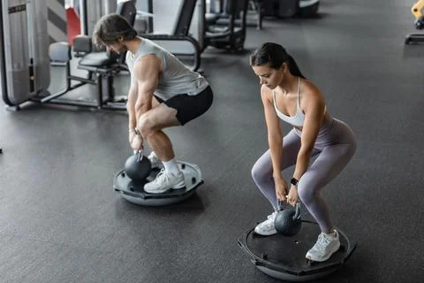 Athletic couple doing exercise on BOSU ball at gym Stock Photos