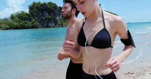 Athletic couple running on Ao Nang beach on holiday in Thailand , wearing wearab Video stock 201094598