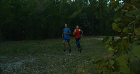 Athletic couple running trough a forrest at sunset Stock Footage 104231337
