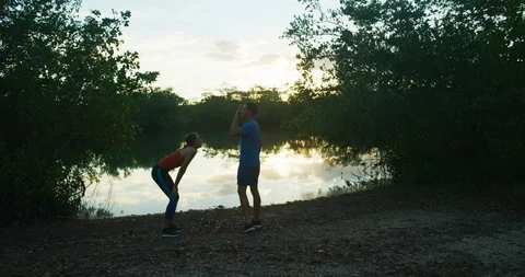 Athletic couple taking a break from jogging in a forrest at sunset Stock Footage 104228768