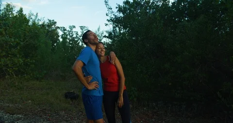 Athletic couple taking a break from jogging in a forrest at sunset Stock Footage 104228892