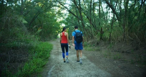 Athletic couple walking through a forrest together, shot from behind Stock Footage 104232257