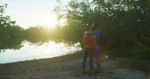 Athletic couple watching the sunset over a lake in a forrest Stock Footage 104229539