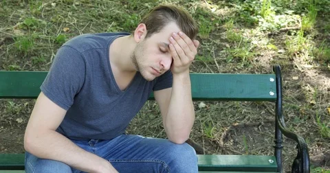 Athletic Cute Guy Suffer Alone Sitting on a Comfortable Park Bench Headache Pain Video stock 77006781
