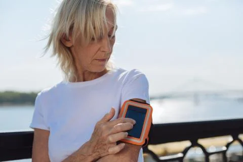 Athletic elderly lady tracking distances with phone in arm band Stock Photos
