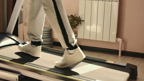 Athletic feet running on treadmill in in front window at home in white shoes Stock Footage 132648481