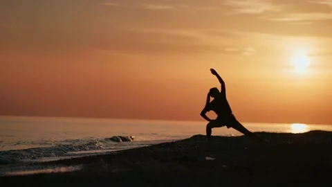 Athletic female doing yoga exercise stretching body at sunset beach. Shot with Stock Footage 143630902