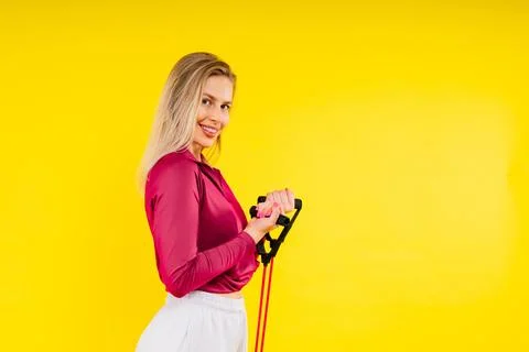 Athletic female performs exercises using a resistance band. Strength and Stock Photos