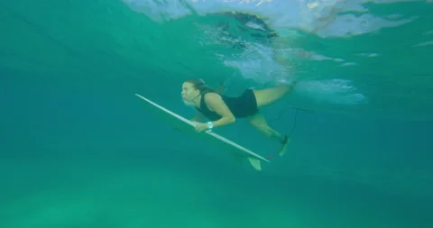Athletic female surfer diving under ocean wave and swimming with surfboard in Au Stock Footage 199458479