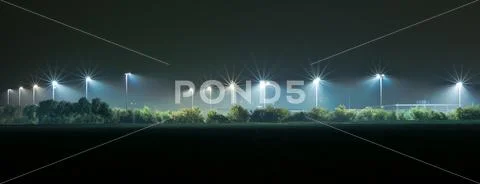 Athletic field illuminated by bright lights in the dark Stock Photos