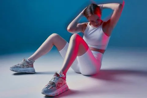 Athletic fit girl does exercise for abdominal muscles in fitness studio. Sport Stock Photos