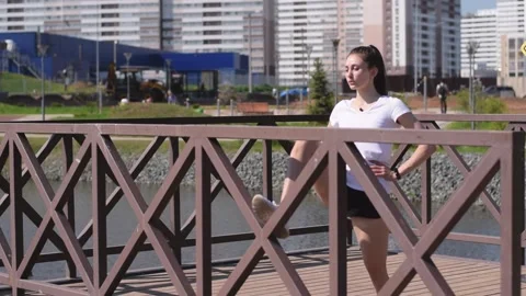 Athletic girl doing a leg stretch on the pier on the shore of pond. Stock Footage 154846513