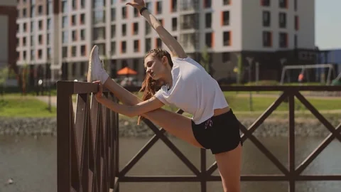 Athletic girl doing a leg stretch on the pier on the shore of pond. Stock Footage 154846522