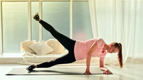 An Athletic Girl Doing Side Plank Core Strength Training at Home Alone. Sport Stock Footage 153952991