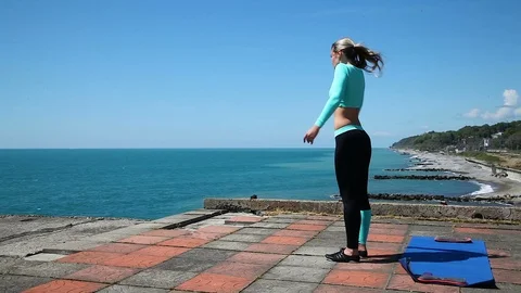 Athletic girl doing a warm-up on the beach, wind and sun Stock Footage 114548484