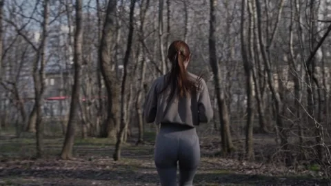 Athletic girl dynamically running in the park between the trees. Stock Footage 272191496