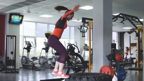 Athletic girl jumping on a large tractor wheel. Stock Footage
