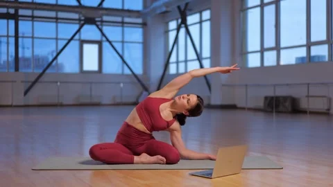 Athletic girl teaches an online lesson yoga asana with laptop Stock Footage 260774053