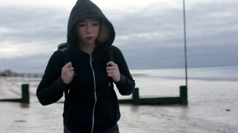 Athletic girl woman in hoodie walks on beach with kit bag on shoulder 4k Stock Footage