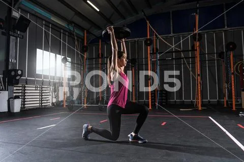 Athletic girl works out at the gym with a barbell disk Stock Photos