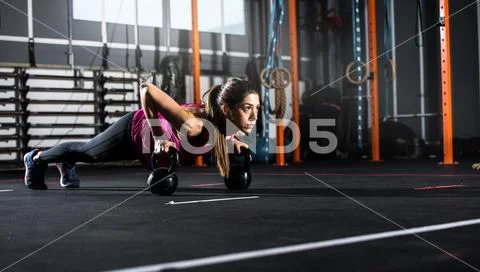 Athletic girl works out at the gym with a kettlebell Stock Photos