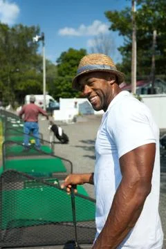 Athletic golfer swinging at the driving range dressed in casual attire. Stock Photos