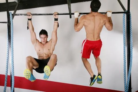 Athletic group executing exercise tightening on horizontal bar. pull ups and Stock Photos