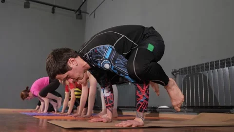 Athletic guy in black tracksuit performs yoga exercise Stock Footage 155428421