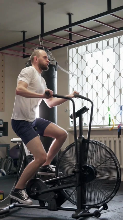 Athletic guy doing cardio workout on exercise bike. Motivation and strength. Stock Footage 302433239